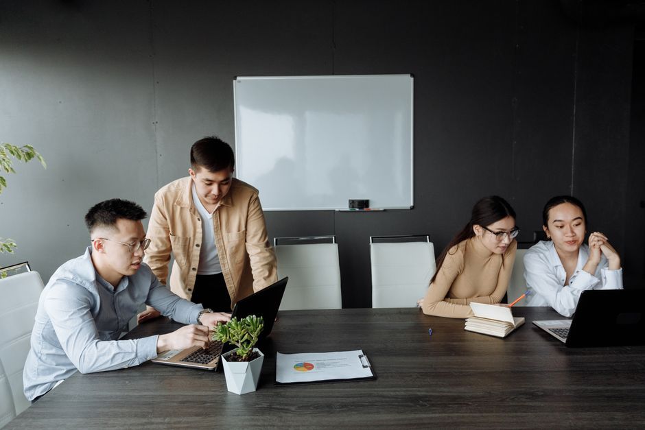 Group of diverse colleagues brainstorming and working on laptops in a modern office setting.