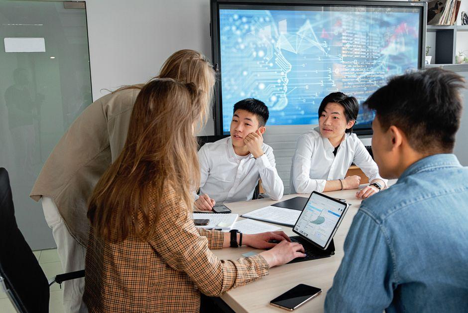Team of professionals collaborating in an office with digital interface on background screen.