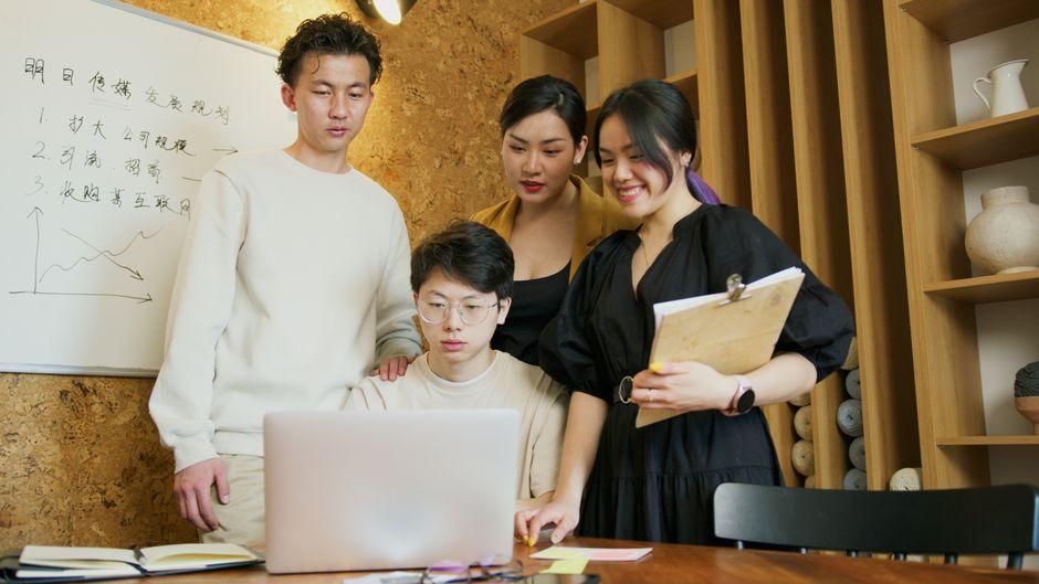 A group of young professionals working together on a project in a modern office setting.