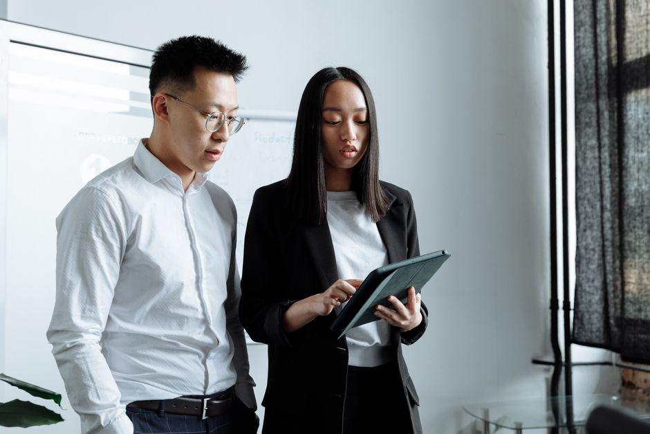 Two business people discussing work on a tablet in a modern office setting.